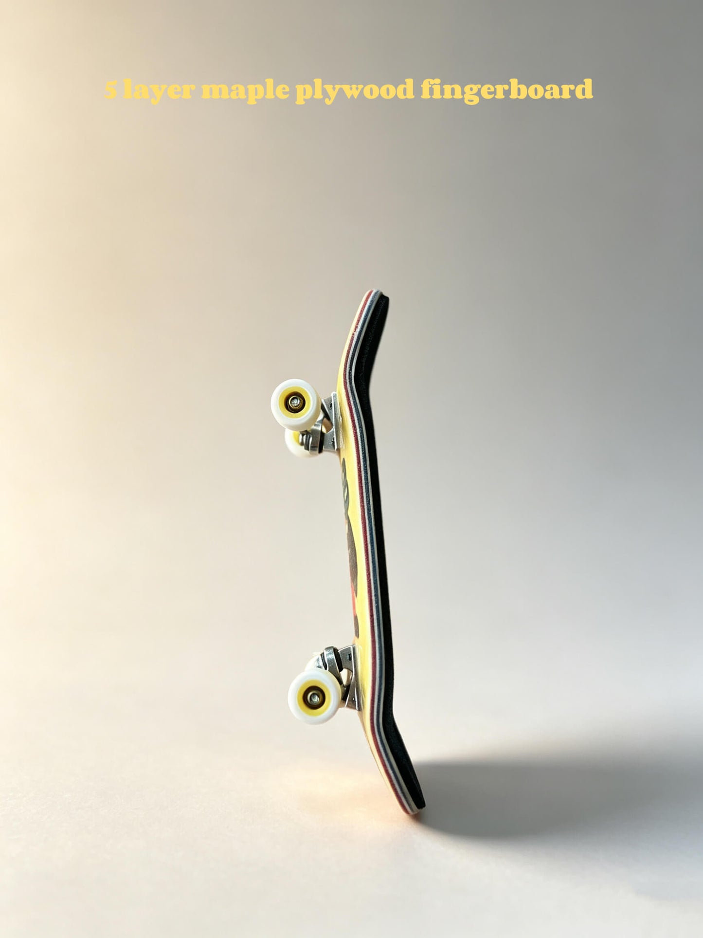 Close‑up fingerboard edge, multi‑layer maple wood ply, metal trucks and bearing wheels