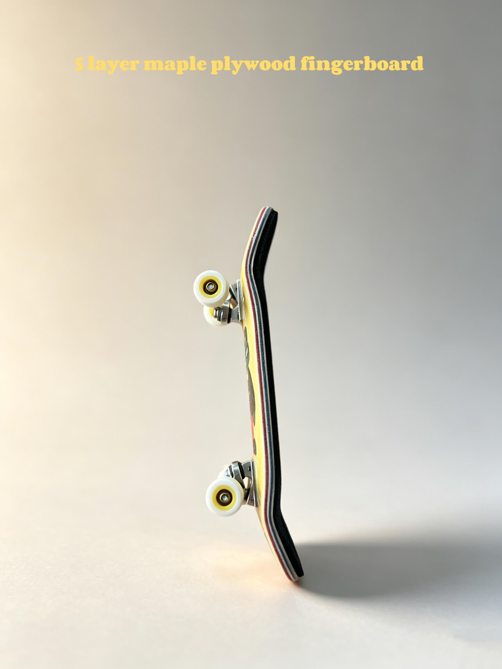 Close‑up fingerboard edge, multi‑layer maple wood ply, metal trucks and bearing wheels